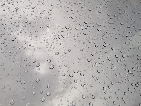 Raindrops on window glasses with cloudy sky background. Stock Photos
