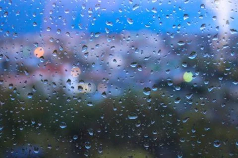 Raindrops on window glasses surface with blurred cityscape background Stock Photos
