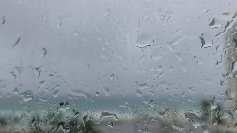 Raindrops on window with moving car lights blurred city street rainy night atmos Stock Footage 331347327