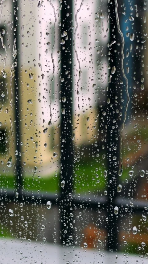 Raindrops on window overlooking balcony, blurred railings and green lawn visible Stock-Footage 344732411