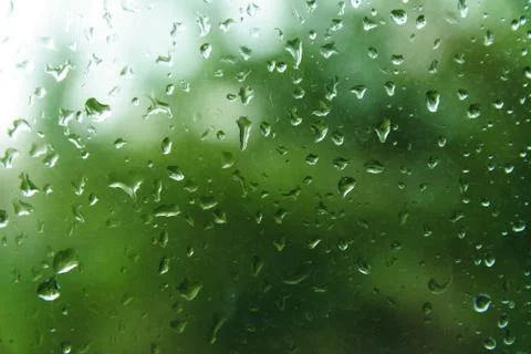 Raindrops on window pane with blurred background. Stock Photos