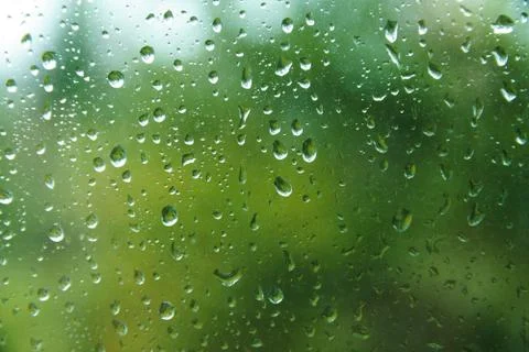 Raindrops on window pane with blurred background. Stock Photos