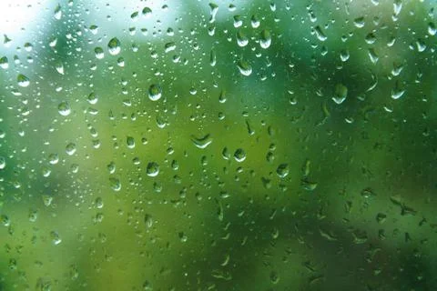 Raindrops on window pane with blurred background. Stock Photos