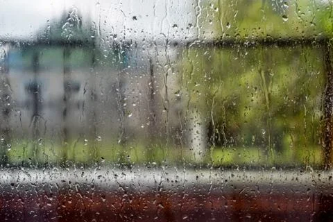 Raindrops on window pane. Blurred background outside the window in the rain. Stock Photos