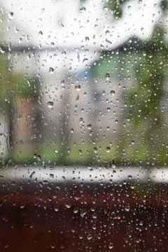 Raindrops on window pane. Blurred background outside the window in the rain. Stock Photos