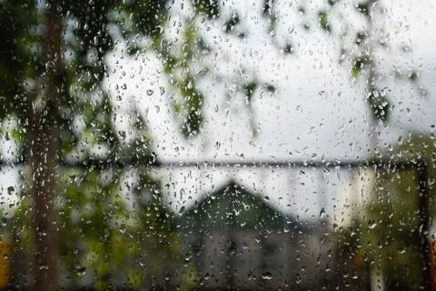 Raindrops on window pane. Blurred background outside the window in the rain. Stock Photos