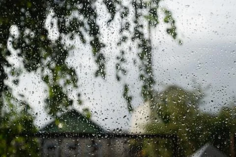 Raindrops on window pane. Blurred background outside the window in the rain. Stock Photos
