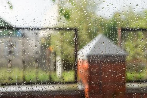 Raindrops on window pane. Blurred background outside the window in the rain. Stock Photos