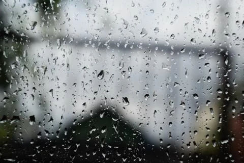 Raindrops on window pane. Blurred background outside the window in the rain. Stock Photos