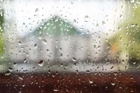 Raindrops on window pane. Blurred background outside the window in the rain. Stock Photos
