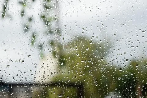 Raindrops on window pane. Blurred background outside the window in the rain. Stock Photos