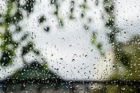 Raindrops on window pane. Blurred background outside the window in the rain. Stock Photos