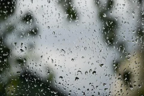 Raindrops on window pane. Blurred background outside the window in the rain. Stock Photos