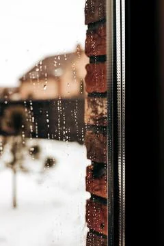 Raindrops on a window pane with a blurred brick wall background Stock Photos