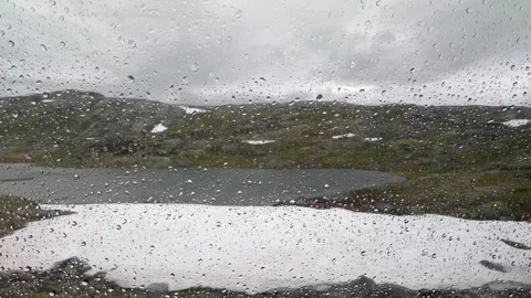 Raindrops on a window pane with a blurred natural landscape Stock Footage 314073455