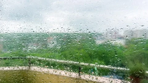 Raindrops on a window pane focus on a blurry green background.  Vidéo 338241437