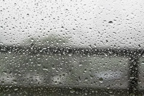 Raindrops on window pane with white mist on balcony railing background Stock Photos
