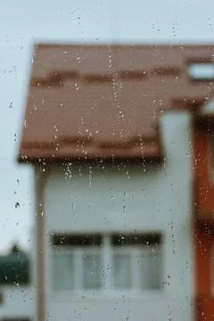 Raindrops on window. Rooftop of building in defocus. Gloomy rainy autumn weather Stock Photos