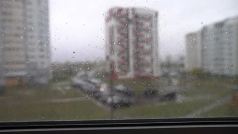Raindrops on the window show buildings and parked cars outside in a city. The Stock Footage 336016892