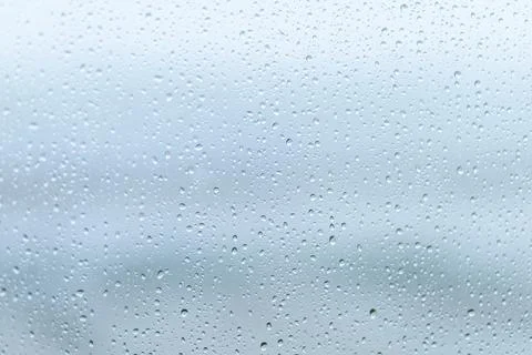 Raindrops on a windowpane create a serene atmosphere during a cloudy day Stock Photos
