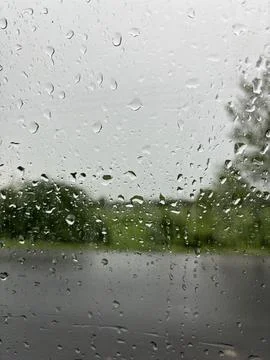 Raindrops on a windowpane overlooking blurred trees Stock Photos
