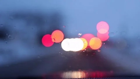 Raindrops on windshield with blurred traffic lights ahead.  Stock Footage 329624788