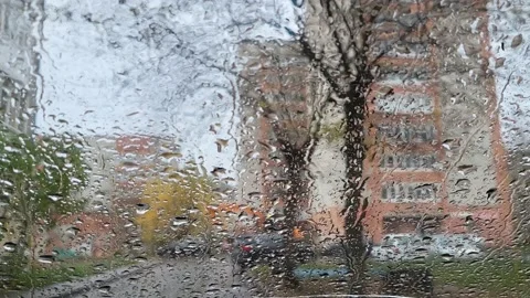 Raindrops on the windshield blurred the view of city houses Stock Footage 232717848