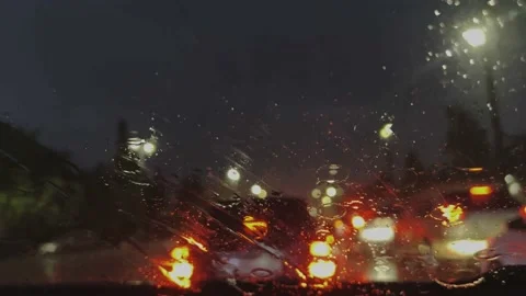 Raindrops on the windshield of the car. The car is driving through the streets. Video stock 202606529