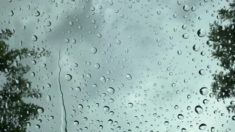 Raindrops on a windshield with dark overcast sky and tree silhouettes. Stock Footage 345665120