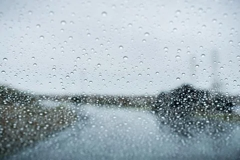 Raindrops on the windshield on a rainy day; empty street in the background;.. Stock Photos