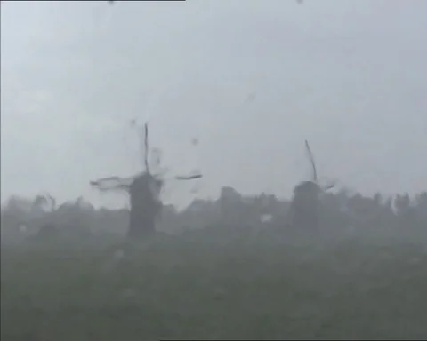 Rainfall against glass window - a view at rainy Kinderdijk windmills Stock Footage 113400035