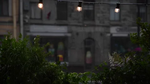 Rainfall in city with cozy lights and lush greenery Stock Footage 302113552