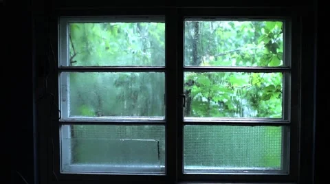 Rainfall that falls down over a dark window from a dark room beyond which is Stock Footage 64859757