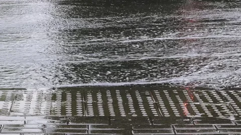 Rainfall on street surface with water puddles and ripples, showing reflections Stock Footage 339865077