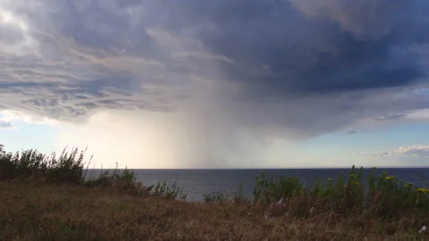 Raining on one spot on the ocean view from the shore Stock Footage 130881350