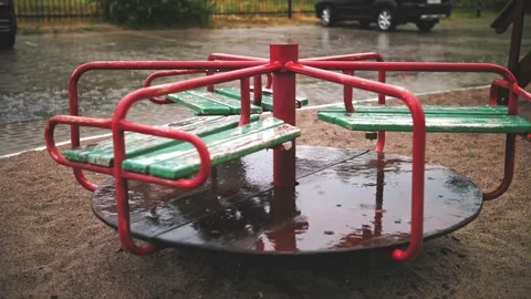 Raining on playground. close-up. Wet, empty merry go round carousel , in the Stock Footage 159375940