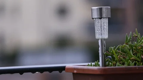 Raining on a solar lamp impaled to a flower pot Stock Footage 121508538