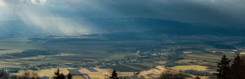 Raining sunbeams between storm clouds over a mountain range. Stock Photos
