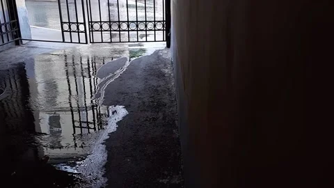 Raining. Wet street with reflections of walking people. Looking through gate. Stock-Footage 135167512