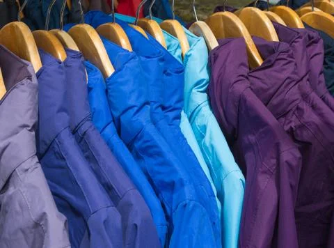 Rainproof jackets in bright colors on a rack for sale. Stock Photos