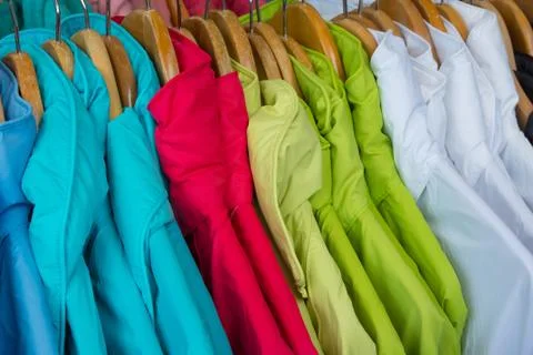 Rainproof jackets in bright colors on a rack for sale. Stock Photos