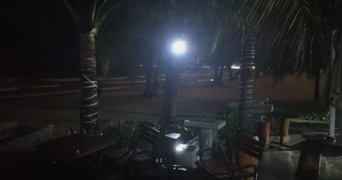 Rain‑soaked terrace, empty tables, dark windy beach. Stock Footage 338146865