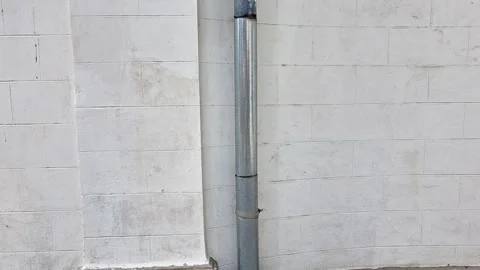 Rainwater Downspout Drainpipe on White Building Wall and Cobblestones Stock Footage 340249006