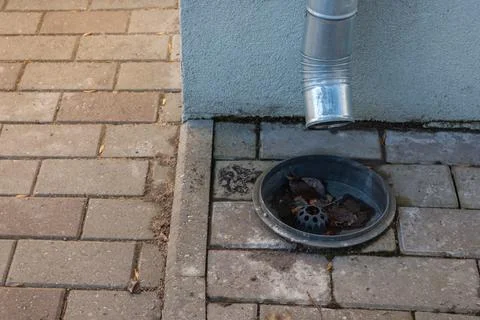 Rainwater drain receiver on paved surface near building Stock Photos
