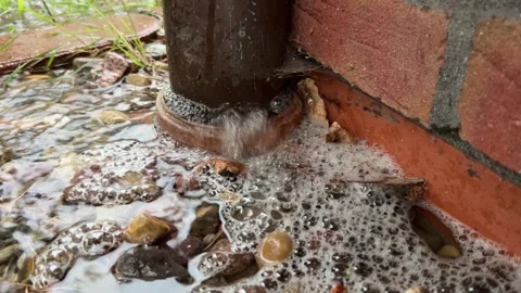 Rainwater flowing from drainage pipe over stones Stock Footage 344798991