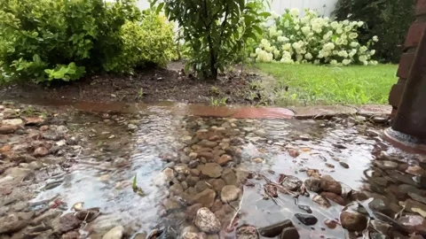 Rainwater flowing through a stone garden drainage area Stock Footage 344798835