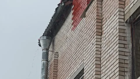 Rainwater flows from a metal gutter down the side of a brick building Stock Footage 336686958