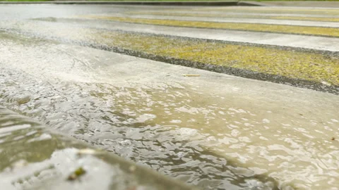 Rainwater flows rapidly along a city crosswalk during a heavy storm Stock Footage 336093851