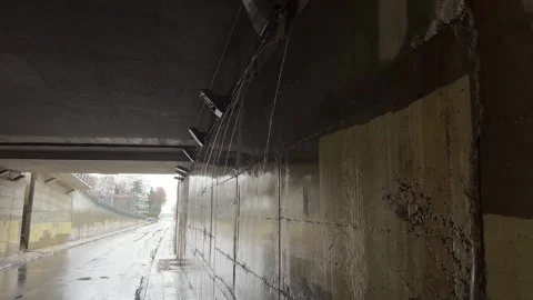 Rainwater stream flowing through urban tunnel illuminated by natural light Stock Footage 325518851