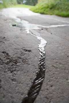 Rainwater Streaming down Asphalt Stock Photos